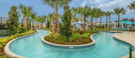 A curved swimming pool with palm trees and a covered seating area.
