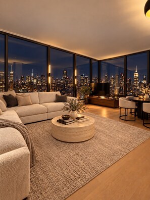 A modern living room with a large window overlooking a cityscape at night.
