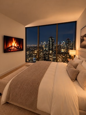 A bedroom with a city view, a fireplace, and a large bed.