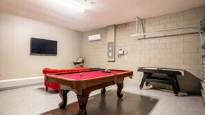 A pool table with a red felt surface, a billiards table, and a television mounted on the wall. - 6BR Home w/ Private Pool Near Disney (Kissimmee)