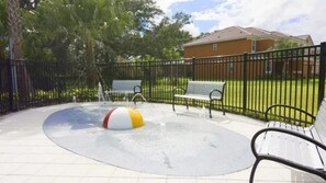 A fenced outdoor area with a water feature, benches, and a building in the background. - 6BR Home w/ Private Pool Near Disney (Kissimmee)
