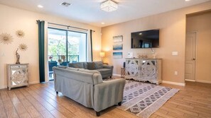 A living room with a sofa, a TV, a cabinet, and a patterned rug. - 6BR Home w/ Private Pool Near Disney (Kissimmee)