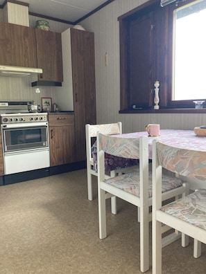 A kitchen with a stove, cabinets, and a dining table with chairs.
