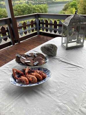 A table with seafood dishes, a lantern, and a view of a lake. - Cozy vacation rental on the Langfjord in Vistdal with panoramic views (Møre og Romsdal)