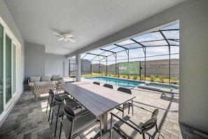 Eine Außenpatio mit Pool, Essbereich und großem Fenster mit Blick auf ein Sportfeld.