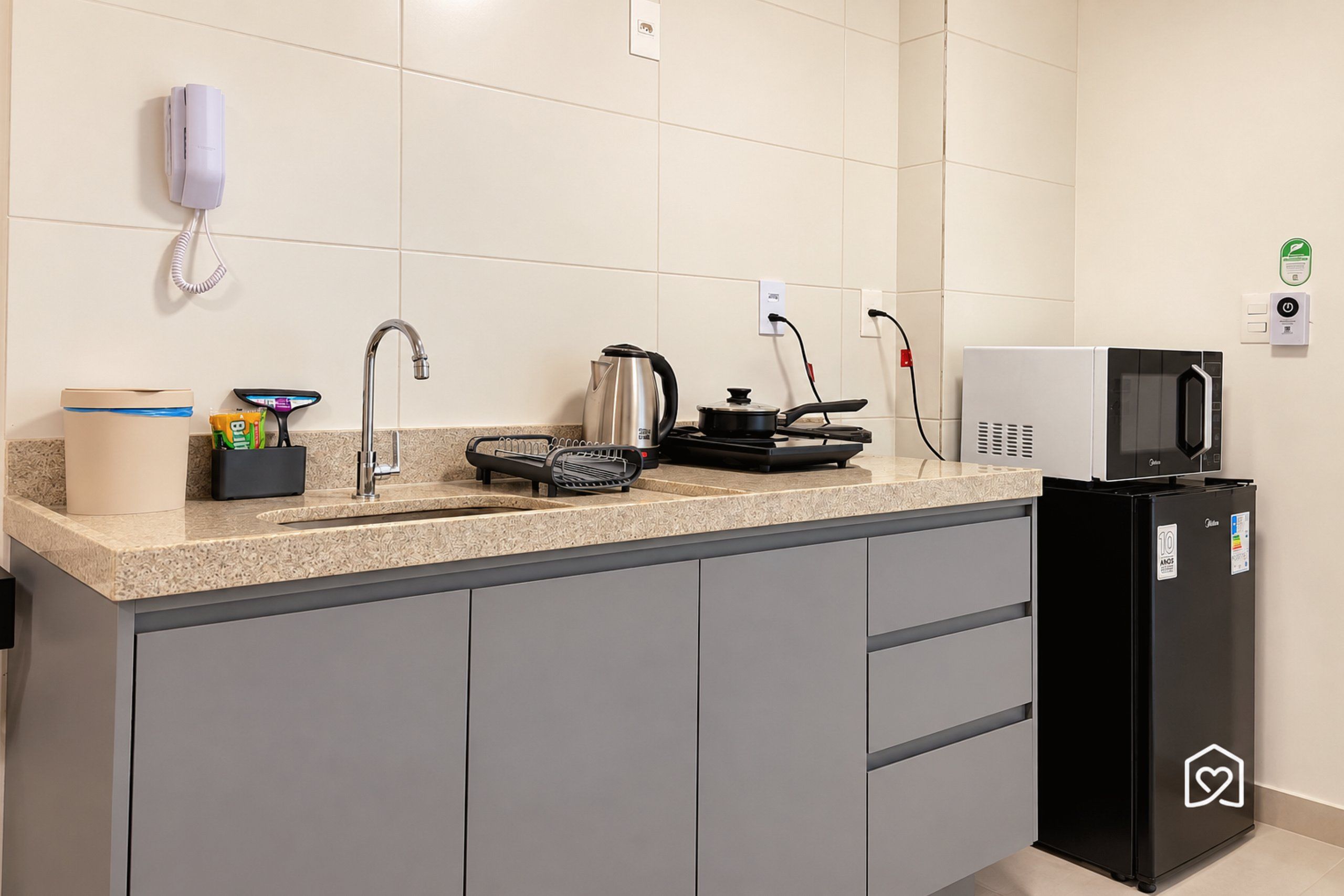 Una cocina moderna con microondas integrado, hervidor de agua y soporte para hervidor.