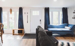 En stue med sofa, bænk og dør.