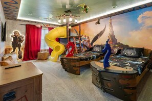 A child's bedroom with a slide, a bed with a 'Captain' themed design, and a mural of a castle. - Solara 9BR Luxury + Game Room & Pool (Kissimmee)