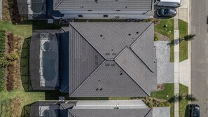 An aerial view of a building with a symmetrical roof design, a parking area, and surrounding greenery. - Luxury 8BR Villa w/ Cinema, Game Room, Pool (Orlando)