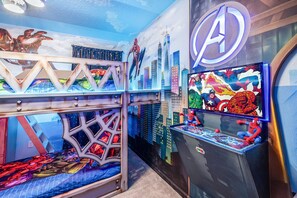 A children's room with bunk beds, a mural of a cityscape, and a large Avengers logo. - Luxury 8BR Villa w/ Cinema, Game Room, Pool (Orlando)
