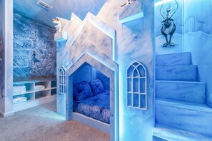 A children's bedroom with a bed, built-in shelving, and a mural on the wall. - Luxury 8BR Villa w/ Cinema, Game Room, Pool (Orlando)
