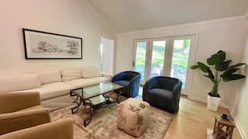 A living room with a sofa, armchairs, a coffee table, and a large potted plant.