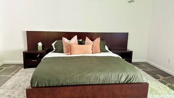 Une chambre à coucher avec un grand lit, une tête de lit en bois foncé, deux tables de chevet et un tapis à motifs.