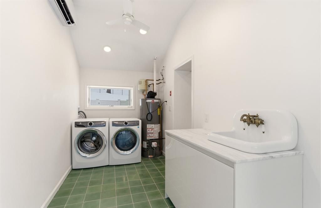 Bright laundry with washer/dryer, utility sink, AC, and storage.