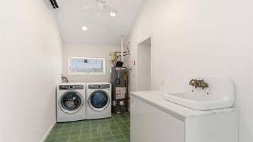 Bright laundry with washer/dryer, utility sink, AC, and storage.