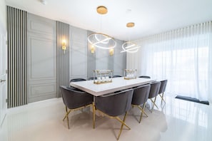A dining area with a white table, black chairs, and gold accents. - Storey Lake 9BR Home w/ Pool & Epic Game Room (Kissimmee)
