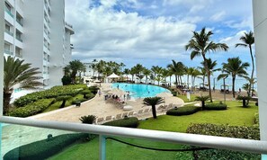 A pool area with palm trees, lounge chairs, and a view of the beach. - Beachfront Bliss, Sea view and pools (Playa Juan Dolio)