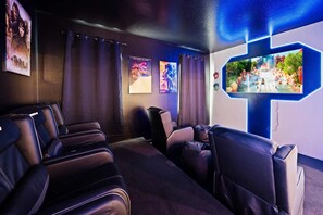 Une salle de cinéma privée équipée de fauteuils en cuir inclinables, d’un grand téléviseur à écran plat et de posters encadrés accrochés au mur.