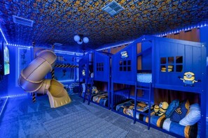 Ein Kinderspielzimmer mit Etagenbetten, einer Rutsche und Minion-Dekorationen.