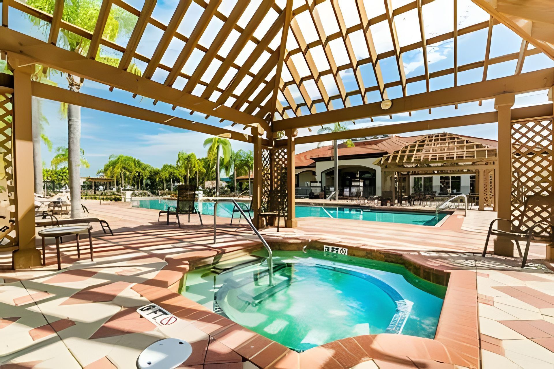 A covered outdoor pool area with a hot tub, lounge chairs, and a pool table.