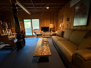 A cozy living room with a sofa, a television, and a rocking chair. - Carrabassett Cabin | Minutes to Sugarloaf (Carrabassett Valley)