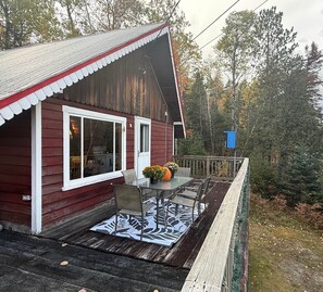 A wooden cabin with a porch, a table with chairs, and a blue mailbox. - Carrabassett Cabin | Minutes to Sugarloaf (Carrabassett Valley)