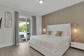A modern bedroom with a large bed, a sliding glass door to a balcony, and a minimalist decor. - 9BR Villa w/ Pool & Spa (Kissimmee)