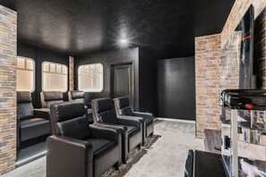 A home theater room with leather recliners, a brick wall, and a ceiling-mounted projector. - Luxury 10br w/ Pool, Theater & Game Room (Clermont)