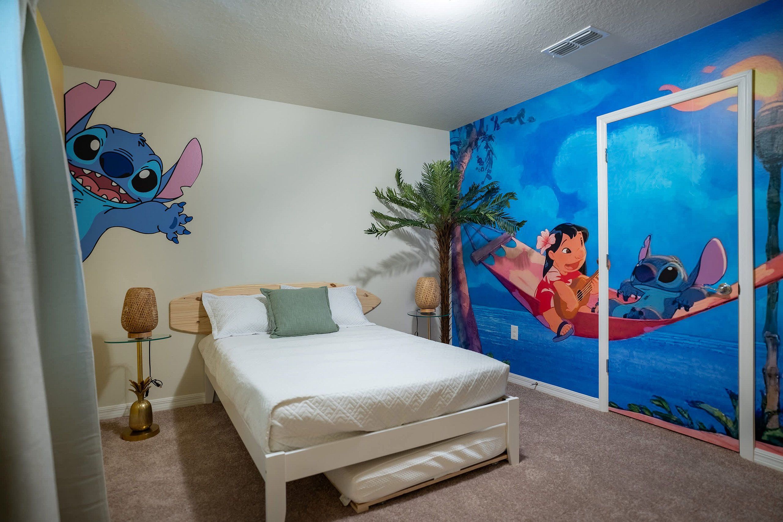 Quarto com cama, mesa de cabeceira, abajur, painel na parede e uma porta.