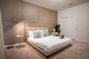 A bedroom with a bed, bedside table, lamp, and a potted plant. - 10br Windsor Cay Resort Home + Private Pool (Clermont)