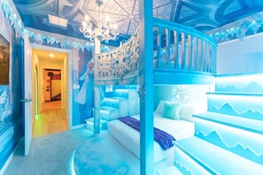 A room with a spiral staircase, a bed with a blue blanket, and a chandelier. - 10br Themed Villa + Pool Theater & Pizza Oven (Clermont)