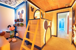 Ein Spielbereich für Kinder mit einem Basketballkorb, einer Kletterleiter und einer Mickey-Mouse-Statue.
