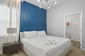A modern hotel room with a large bed, a bedside table with a lamp, and a blue accent wall. - Solterra 12 BDR 10 Suites 29 Guests Pool/spa (Davenport)