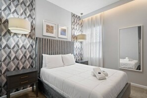 A hotel room with a bed, bedside tables, a mirror, and wall art. - Solterra 12 BDR 10 Suites 29 Guests Pool/spa (Davenport)