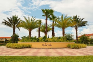 A landscaped area with palm trees and a sign that reads 'Bella Vida.' - House 12Q With Pool With Heating - and Game Room (Kissimmee)