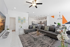 A modern living room with a sectional sofa, a glass coffee table, and a ceiling fan. - House 12Q With Pool With Heating - and Game Room (Kissimmee)