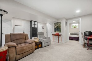A living room with a sofa, armchair, and a small table with a lamp. - Little Red | Hot Tub | Fire Pit | Waskasoo | Yard (Red Deer)