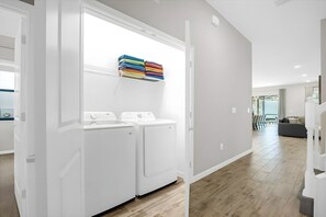 A laundry area with two white washing machines and a stack of colorful towels on a white wall. - 12br Home at Paradiso Grande, Near Disney (Orlando)
