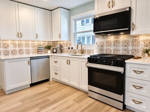 A modern kitchen with white cabinetry, a stainless steel stove, and a black microwave. - Private Lake Access, Renovated Home, Walk Downtown (Beaver Dam)