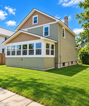 A two-story house with a front porch, a chimney, and a well-maintained lawn. - Private Lake Access, Renovated Home, Walk Downtown (Beaver Dam)