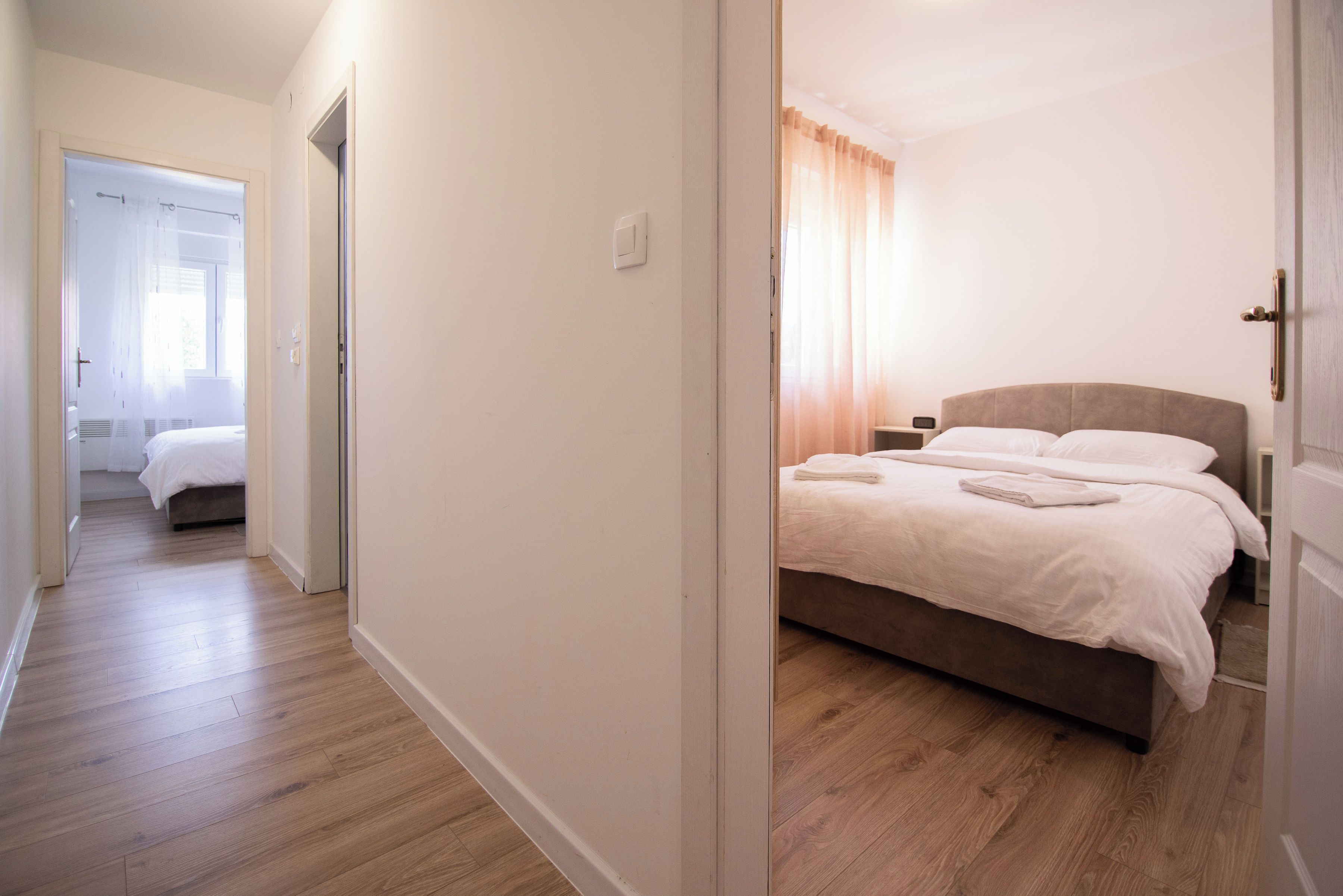 A hotel room with a bed, a bedside table, and a window with curtains.