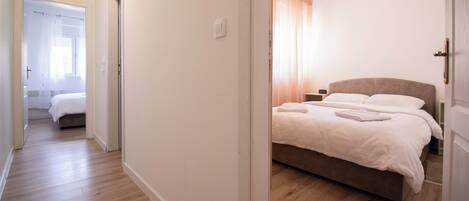 A hotel room with a bed, a bedside table, and a window with curtains.
