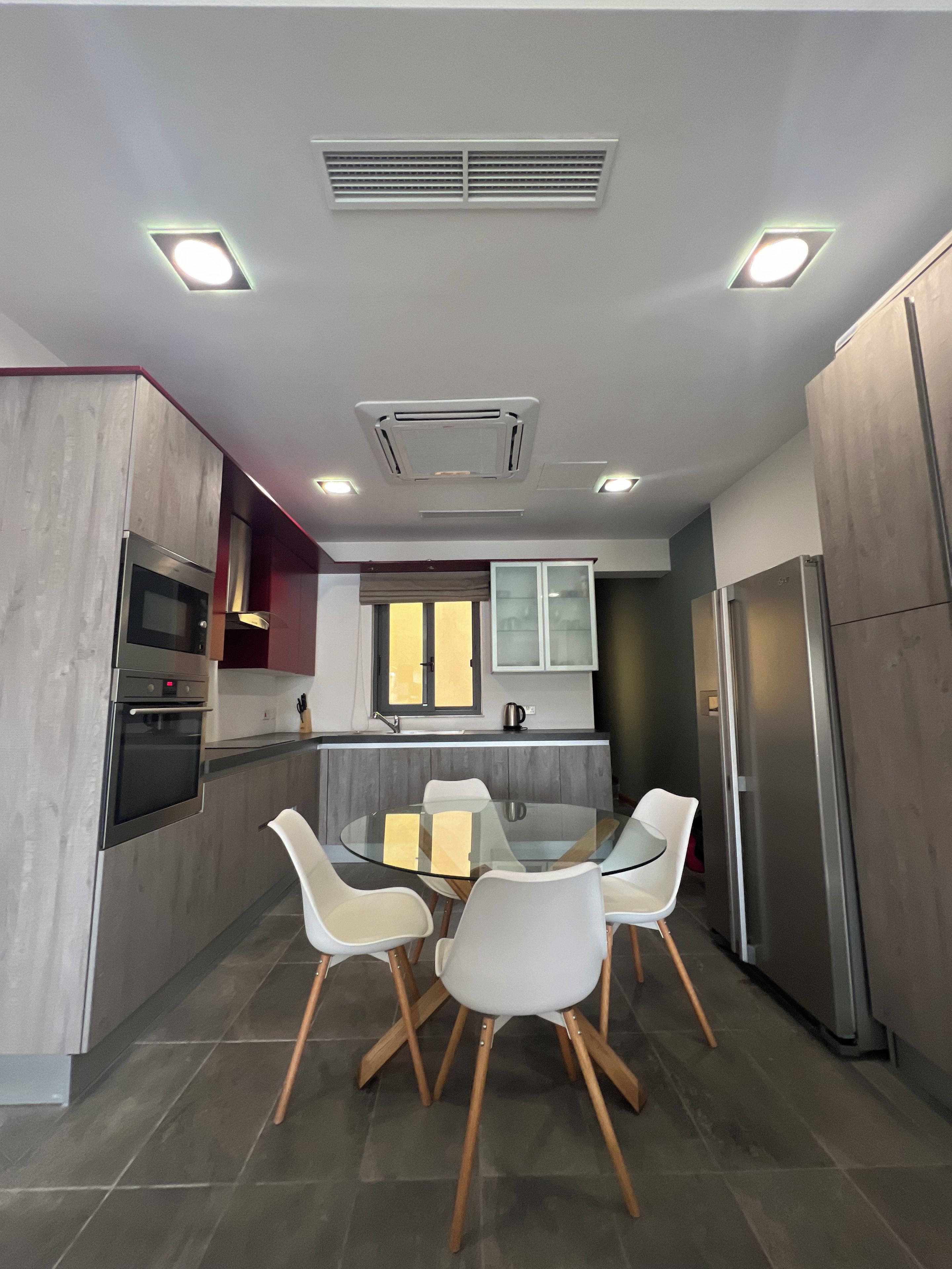 A modern kitchen with a central island, stainless steel appliances, and a dining area with white chairs.