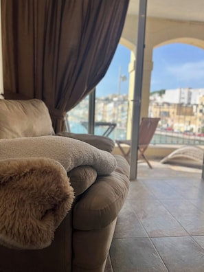 Un balcón con vistas a la ciudad, un sofá con una manta de piel y una silla.