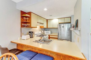 Eine kompakte Küche mit einer zentralen Kochinsel, einer Mikrowelle, einem Toaster und einem Kühlschrank.