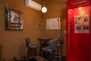 A small room with a red telephone booth, a wall-mounted map, and a table with chairs. - Private Pool & Hot Tub, Game Room Near Disney (Davenport)