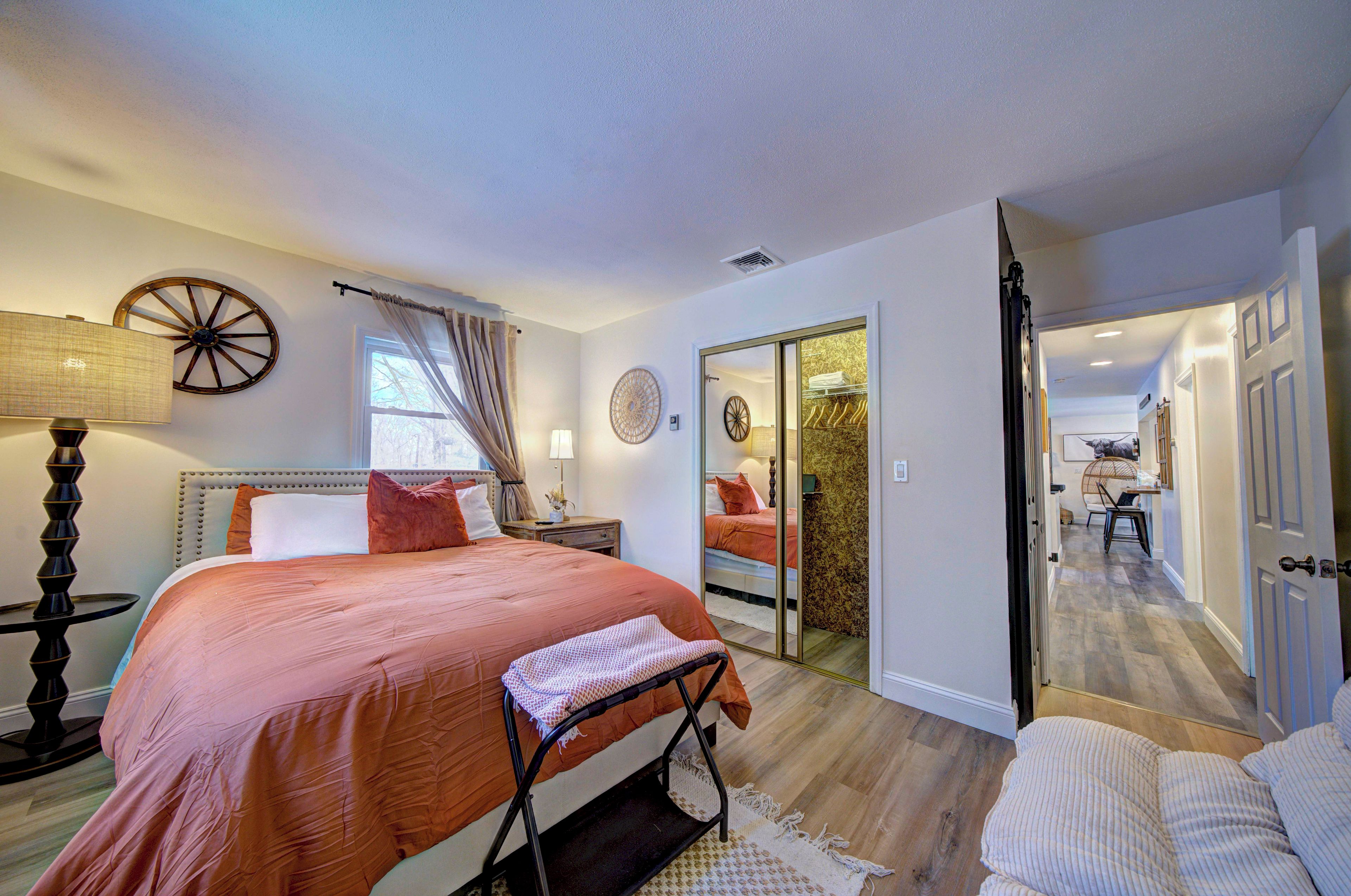 A bedroom with a bed, bedside table, lamp, and a view of a bathroom through a sliding door.