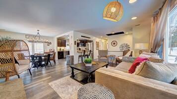 A spacious living area with a dining table, sofas, and a hanging light fixture.