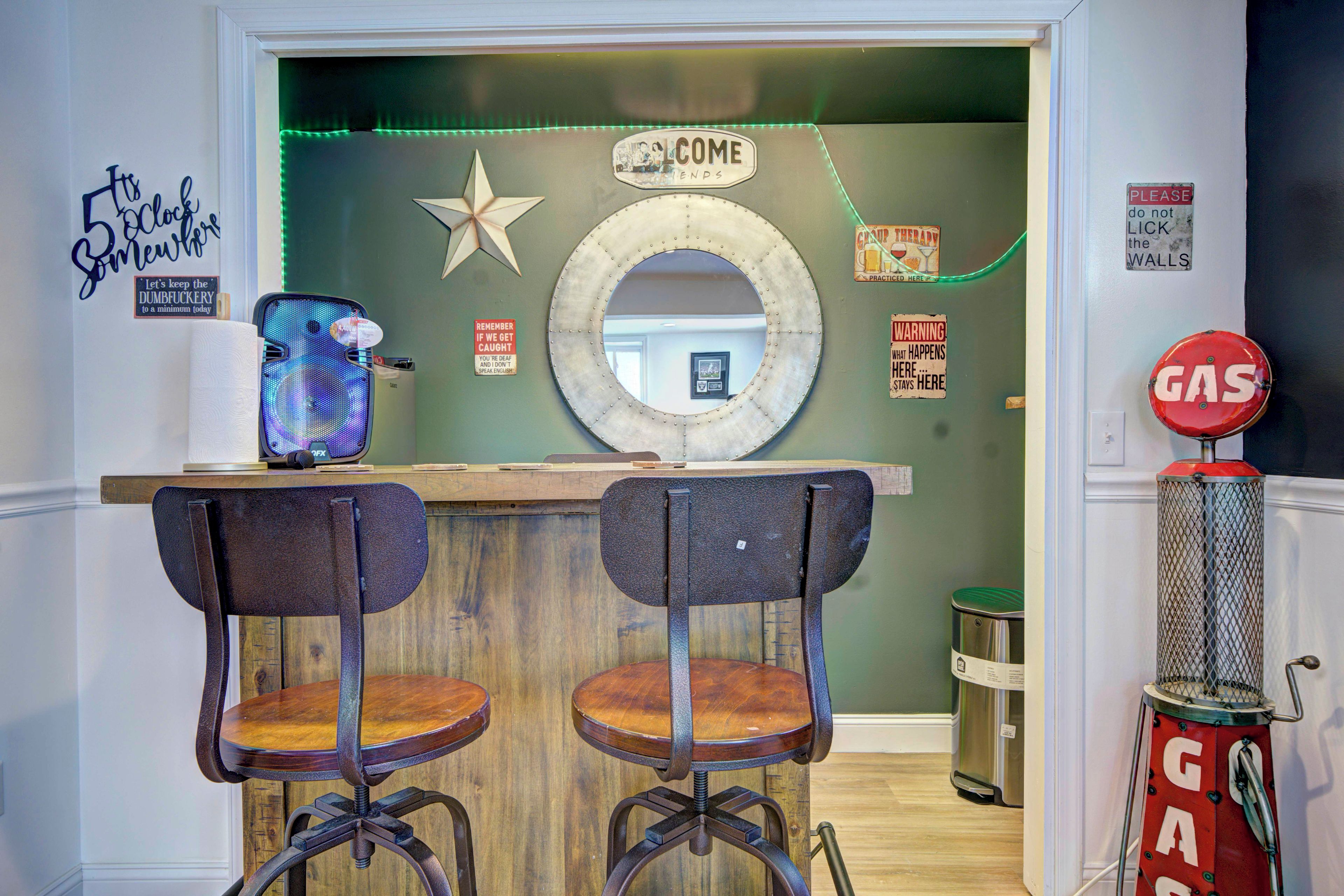 A bar area with two stools, a mirror, and various signs including one that says 'COME'.