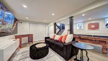 A modern living room with a sofa, ottoman, and a flat-screen TV.
